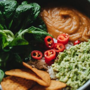 A vibrant vegan Buddha bowl featuring fresh spinach, guacamole, and chili peppers.